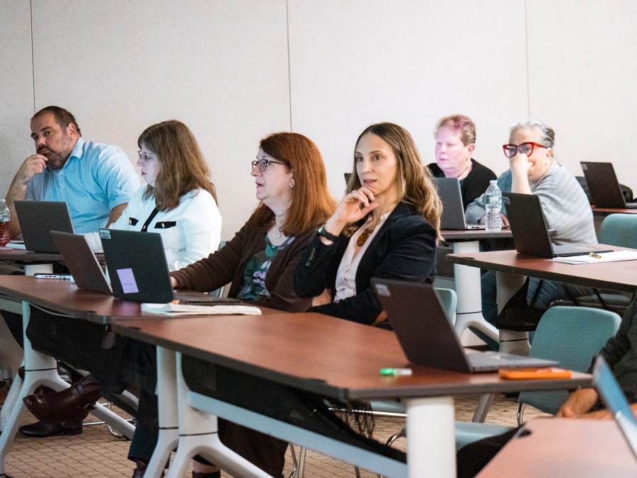 Office staff at laptops during the hands on part of a seminar