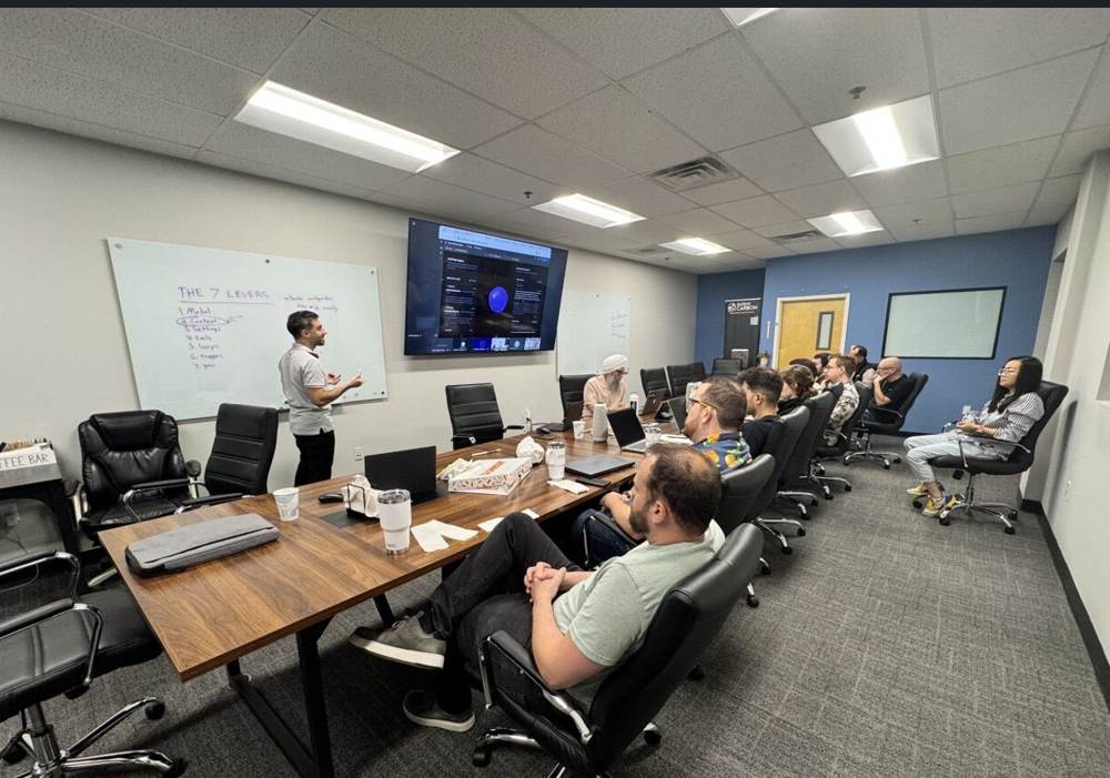 A trainer at a whiteboard while a science team follows on a large screen