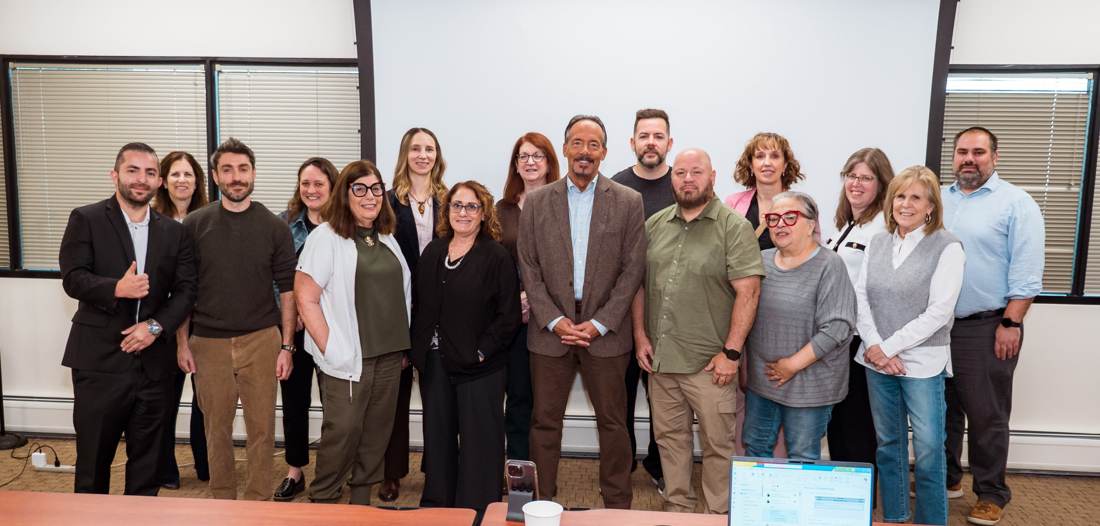 A room of office staff after an AI training seminar, smiling in a group photo